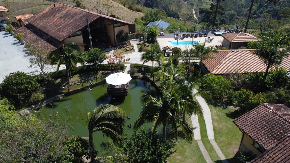 Vista aérea do lodge entre jardins e mata