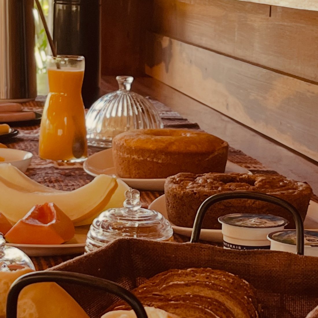 Mesa de café da manhã com bolos, frutas e suco
