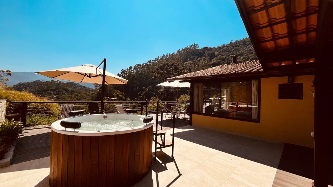 Ofurô no deck da suíte, com guarda-sol e vista para a mata