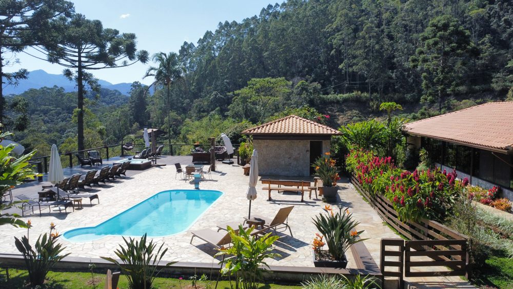 Piscina com espreguiçadeiras e montanhas ao fundo