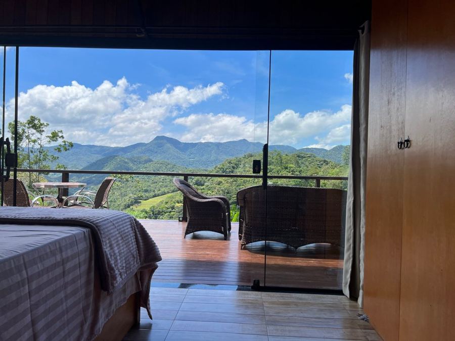 Quarto do chalé aberto para o deck, com as montanhas ao fundo