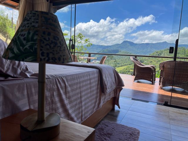 Cama de casal com abajur e vista para as montanhas