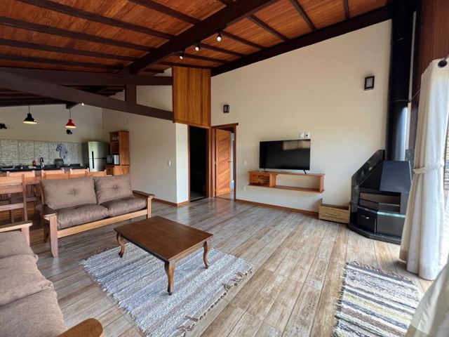 Sala do chalé com sofás, lareira e cozinha