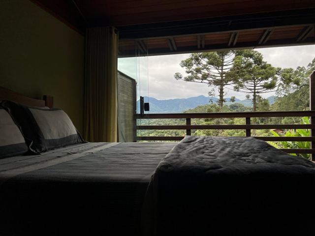 Quarto escuro aberto para as araucárias e as montanhas